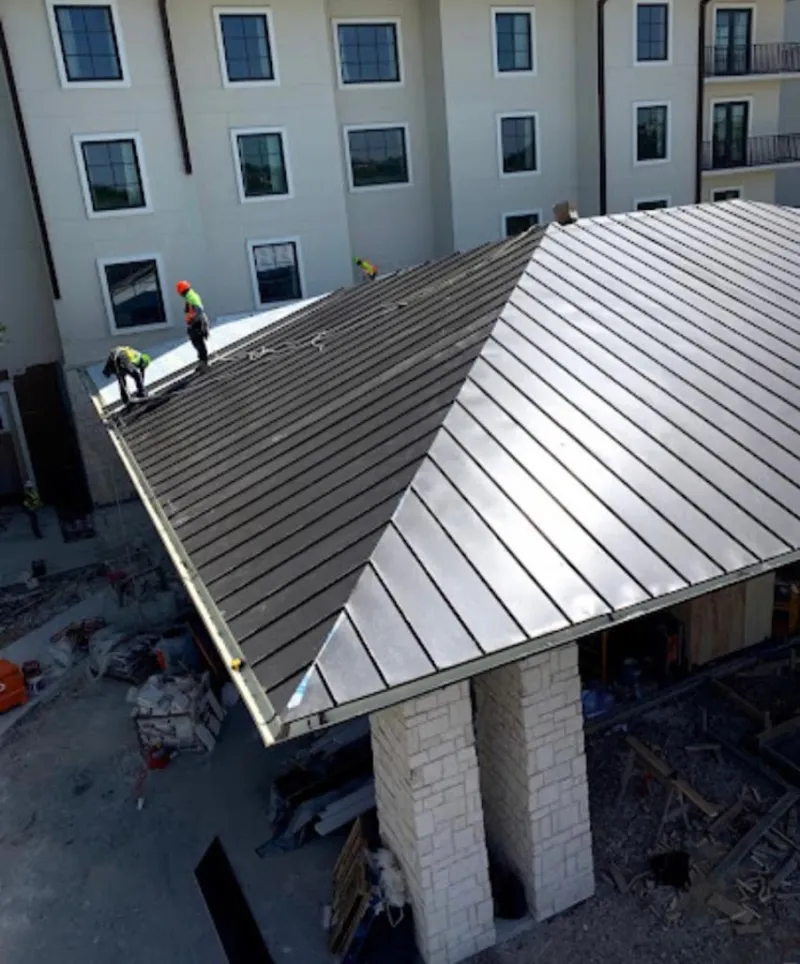 Crew installing standing seam metal roof panels on a commercial project in Terrell Hills